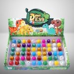 Bunte Dino-Eier in einem offenen Spielzeugkasten mit Dinosaurier-Illustration, ideal für Kinder ab 3 Jahren, fördert Kreativität und Spielspaß.
