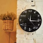 Runde Wanduhr mit schwarzen Ziffern und mathematischen Formeln, dekorativ an einer weißen Ziegelwand, ideal für Wissenschafts- und Mathe-Liebhaber.