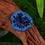 Nahaufnahme eines blauen Kristall-Geodes auf einem Holzstück, detailreiche Textur und funkelnde Kristalle, natürliche Umgebung, wissenschaftliches Dekor.