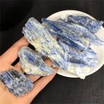 Nahaufnahme von Sodalith-Steinen, die auf einer Hand liegen, mit weiteren Steinen auf einem weißen Teller im Hintergrund, ideal für wissenschaftliche Sammlungen oder Dekoration.