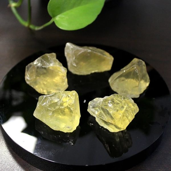 Sechs gelbe, unregelmäßig geformte Kristallstücke auf schwarzem Untergrund, die die natürliche Textur und Transparenz des Minerals zeigen.