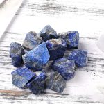 Natürliche blaue Mineraliensteine, unregelmäßig geformt, auf weißem Holzuntergrund, ideal für wissenschaftliche Dekorationen und Sammlungen.