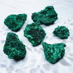 Nahaufnahme von grünen Mineralien mit kristalliner Struktur auf weißem Hintergrund, detailreiche Textur und natürliche Farbgebung.