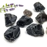 Natürliche schwarze Mineralsteine mit Lavendelzweig, ideal für Dekoration und wissenschaftliche Sammlungen.