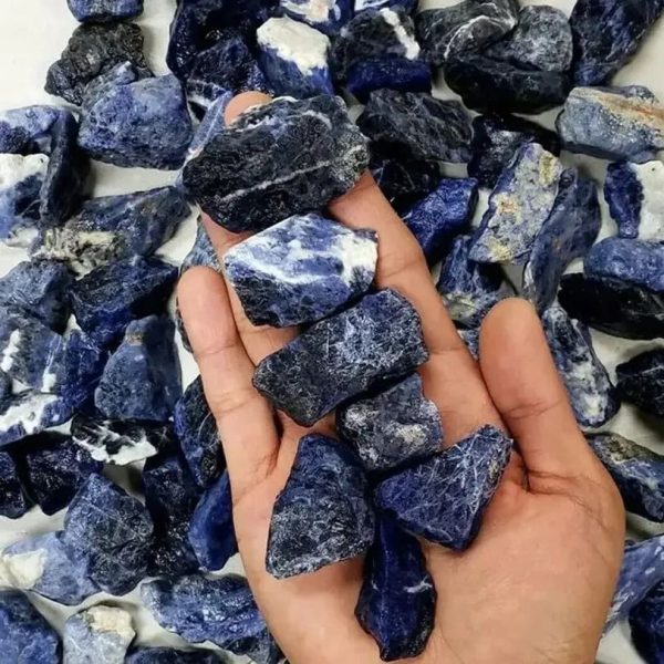 Hand hält mehrere Sodalith-Steine mit blauer und weißer Maserung, umgeben von weiteren Steinen. Perfekt für wissenschaftliche Dekorationen oder Sammlerstücke.