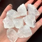 Mehrere große, transparente Quarzkristalle, die in einer Hand gehalten werden, zeigen die natürliche Struktur und Klarheit der Mineralien. Perfekt für wissenschaftliche Dekorationen oder Sammlerstücke.