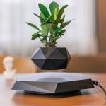 Moderner, geometrischer Blumentopf mit grüner Pflanze auf einem elektronischen Gerät, stilvolle Dekoration für Zuhause oder Büro.