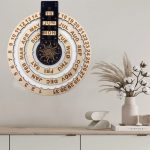 Dekorativer Kalender mit Mondphasen und Jahreszeiten, an der Wand über einem weißen Sideboard, mit einer Vase mit Trockenblumen und einem Buch.