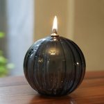 Elegante schwarze Glasvase mit brennender Kerze, ideal für Dekoration und stimmungsvolle Beleuchtung.