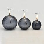 Drei schwarze Kerzengläser in verschiedenen Größen (10cm, 8cm, 6cm) mit brennenden Kerzen, ideal für Dekoration und wissenschaftliche Themen.