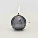Elegante wissenschaftliche Dekoration mit einer schwarzen, runden Glasvase, die eine brennende Kerze trägt, Höhe 8 cm, ideal für stilvolle Raumgestaltung und wissenschaftliche Themen.