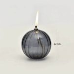 Eleganter Kugel-Kerzenhalter aus Glas mit brennender Kerze, Höhe 12 cm, ideal für wissenschaftliche Dekorationen und moderne Raumgestaltung.