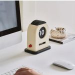 Vintage Zehn-Tage-Timer auf einem weißen Schreibtisch, neben einem Computerbildschirm, einer weißen Computermaus und einem dekorativen Keramikschälchen.