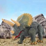 Detailaufnahme eines Dinosaurier-Spielzeugmodells mit Horn und schuppiger Haut, vor einer felsigen Wüstenkulisse.