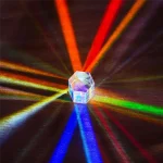 Ein transparenter Kristall, der bunte Lichtstrahlen in alle Richtungen reflektiert, erzeugt ein faszinierendes Lichtspektakel auf einer dunklen Oberfläche.