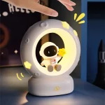 Niedliches Nachtlicht in Astronauten-Design, das den Mond und Sterne zeigt, ideal für Kinderzimmer, mit weichem Licht und Weltraummotiv.