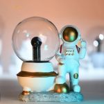 Dekoratives wissenschaftliches Objekt mit einer Astronautenfigur neben einer Glaskugel, ideal für Science-Boutique und Dekorationen.
