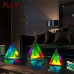 Bunte Glas-Skulpturen in Form von Pyramiden und Schiffen, die farbiges Licht reflektieren, auf einem dunklen Tisch in einem modernen Wohnzimmer.