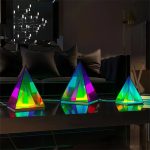 Bunte, leuchtende Kristall-Dekorationen in Pyramidenform, ideal für moderne Wohnräume und wissenschaftliche Dekorationen, mit reflektierenden Oberflächen und LED-Beleuchtung.