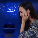 Ein Mädchen bewundert einen Sternenhimmel-Projektor, der leuchtende Sterne und einen Mond an die Decke projiziert, ideal für Schlafzimmerdekoration und entspannende Atmosphäre.
