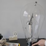 Große Glühbirne mit wissenschaftlichem Experiment, zeigt eine elektrische Vorrichtung in einem transparenten Gehäuse.