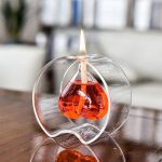 Kleine brennende Kerze in einem tropfenförmigen Glasständer, verwendet als wissenschaftliches Objekt oder Dekoration.