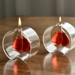 Zwei moderne Kerzenhalter aus transparentem Glas mit brennenden Kerzen, die eine warme Atmosphäre schaffen.