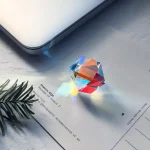 Ein bunter Kristall, der Licht bricht und auf einem Papier liegt, erzeugt ein farbenfrohes Lichtspiel. Perfekt für wissenschaftliche Dekorationen und Gadgets.