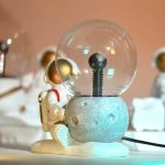 Detailaufnahme einer Raumfahrt-Science-Figur mit einer Glaskugel und einem Astronauten-Design, ideal für Dekorationen und wissenschaftliche Sammlerstücke.