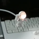 Kleine Raumfahrerlampe mit leuchtendem Kopf, die an einem flexiblen Arm befestigt ist, ideal als dekoratives Licht für Science-Fiction- und Weltraumfans.