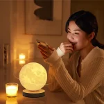 Eine junge Frau nutzt ein Smartphone, während eine realistische Mondphasen-Lampe auf dem Tisch leuchtet, um eine gemütliche Atmosphäre zu schaffen.