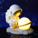 Niedliches Astronautenfigur mit Planetmodell, leuchtend und detailreich, ideal für Weltraumdekorationen und wissenschaftliche Sammlerstücke.