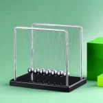 Newton-Wiege mit Metallkugeln auf schwarzem Basis, wissenschaftliches Experiment, Physik, Bildung, Dekoration.