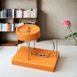 Wissenschaftliches Dekorationsobjekt mit Metallkugeln auf orangefarbenem Basis, ideal für moderne Raumgestaltung.