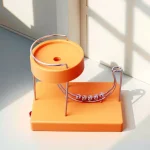 Wissenschaftliches Experimentiergerät mit Metallkugeln auf einer orangefarbenen Basis, ideal für Bildungs- und Dekorationszwecke.