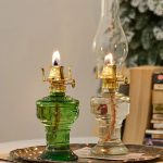 Zwei antike Kerzenleuchter aus Glas, einer grün und einer klar, mit brennenden Kerzen, auf einem silbernen Tablett.