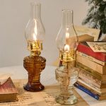 Zwei antike Kerzenlampen aus Glas und Metall, ideal für Vintage-Dekor, auf einem Tisch mit alten Büchern und Notenblättern. Perfekt für nostalgisches Ambiente und stilvolle Raumgestaltung.