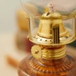 Antike Petroleumlampe mit goldfarbener Metallfassung und Glasabdeckung, ideal für Dekoration und wissenschaftliche Sammlungen.