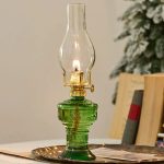 Alt-Öllampe aus grünem Glas mit offener Flamme, dekoratives antikes Design.