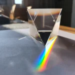 Ein klarer, geometrischer Kristallwürfel, der Licht bricht und einen bunten Regenbogen auf die Oberfläche projiziert. Perfekt für wissenschaftliche Dekorationen und Experimente.