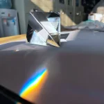 Ein klarer, sternförmiger Glasprisma, das Licht bricht und einen Regenbogen auf die Oberfläche projiziert. Perfekt für wissenschaftliche Dekorationen und Experimente.