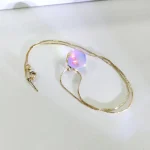 SchmuckstĂŒck mit funkelnder, schillernder Kristallkugel an einer eleganten Goldkette, ideal fĂŒr Wissenschafts- und Dekorationsliebhaber.