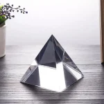 Elegante Kristallglas-Pyramide als dekoratives wissenschaftliches Objekt auf hellem Holzuntergrund, ideal für Sammler und Dekoration.