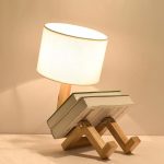Kreative Buchlampe in Form eines sitzenden Menschen, die als dekoratives Lichtstück dient. Perfekt für Bücherliebhaber und moderne Raumdekoration.