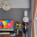 Stilvolle Wohnzimmerdekoration mit Blumenstrauß und modernen Lampen, ergänzt durch einen Fernseher und eine elegante Raumgestaltung.