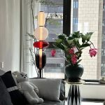 Dekoratives Arrangement mit Blumen und modernen Skulpturen im Wohnzimmer, mit Blick auf Stadtgebäude durch das Fenster.