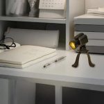 Kleine wissenschaftliche Lampe auf einem Schreibtisch, umgeben von Büchern, Notizen und wissenschaftlichen Dekorationen, ideal für ein wissenschaftliches Arbeitsumfeld.