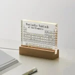 Transparentes Acryl-Objekt mit dem Periodensystem der Elemente, auf einem Holzständer präsentiert, ideal als wissenschaftliche Dekoration oder Lernhilfe.