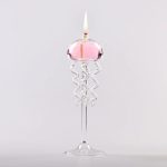 Eleganter Kerzenhalter aus Glas mit spiralförmigen Elementen, der eine brennende Kerze trägt, ideal für wissenschaftliche Dekorationen und elegante Raumgestaltung.