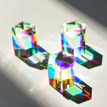 Drei bunte Kristall-Objekte, die Licht brechen und Regenbogeneffekte auf einer glatten Oberfläche erzeugen, ideal für wissenschaftliche Dekorationen und faszinierende Lichteffekte.